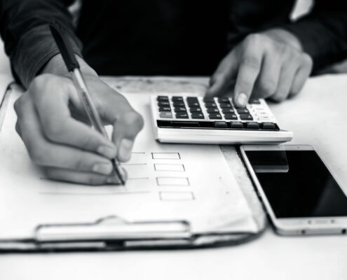 Finance person table's or workplace's close up a shot while he was doing some finance and loan-related work with cell phone, calculator and pages, and pen.